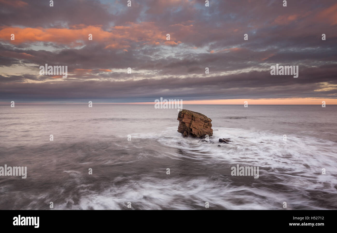 Lone sea stack at Charlie's Garden, Northumberland, at sun set and with the North Sea at high tide. Stock Photo