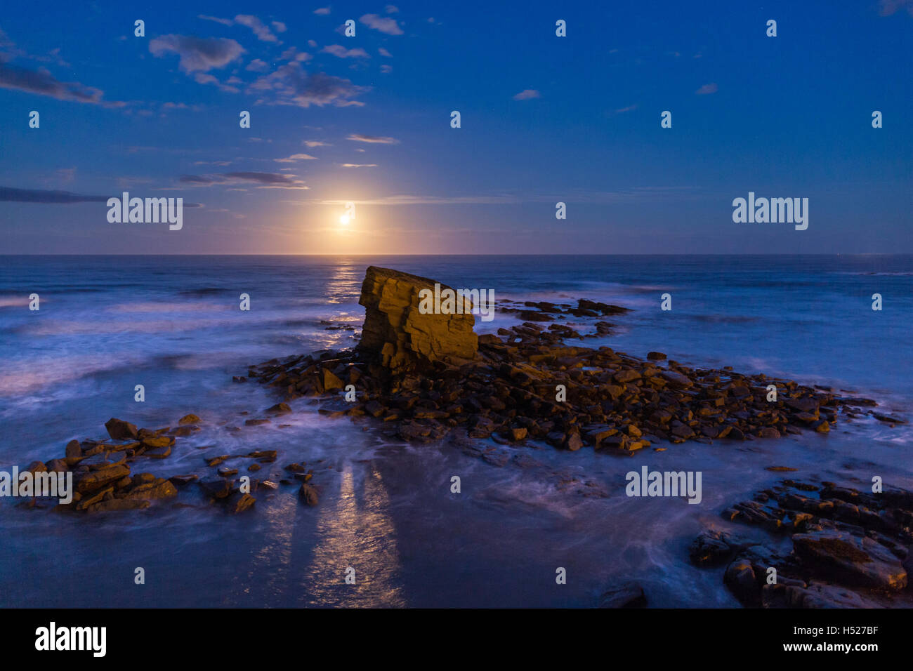 Lone sea stack at Charlie's Garden, Northumberland, at moon rise with the North Sea lit by moon light from a Hunter's Moon. Stock Photo