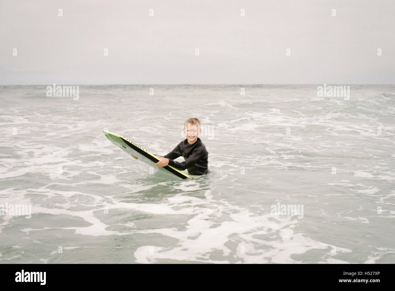 Blond boy bodyboarding in the ocean. Stock Photo