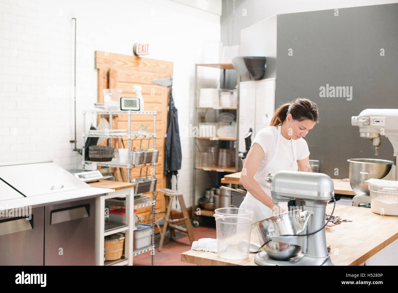 Woman wearing a white apron at a work counter in a bakery. Stock Photo