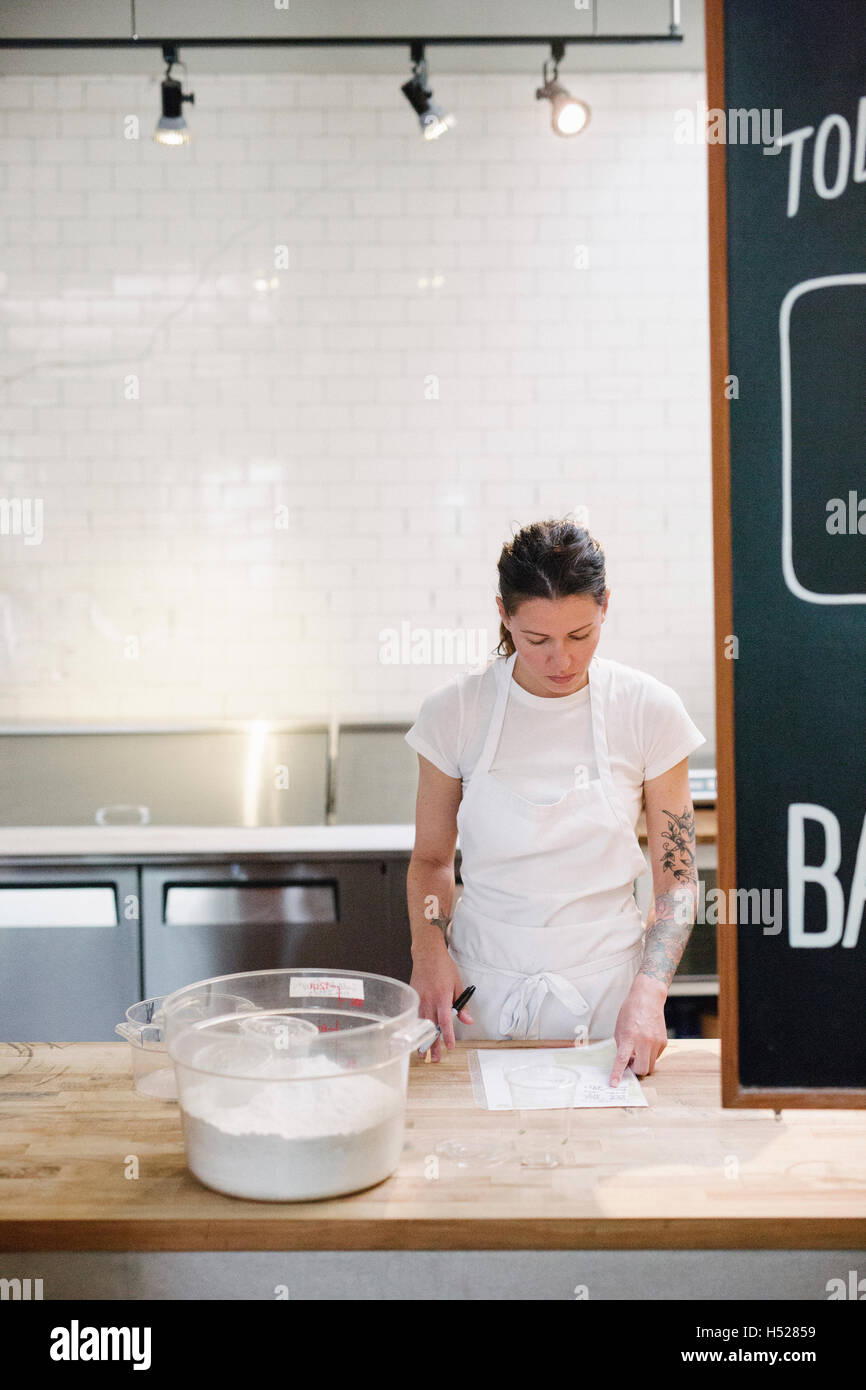 https://c8.alamy.com/comp/H52859/woman-wearing-a-white-apron-at-a-work-counter-in-a-bakery-H52859.jpg