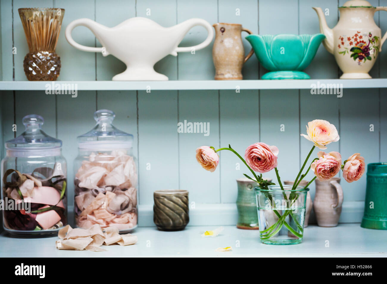 A shelf with vases and ceramic pots, and flowers in a vase Stock Photo