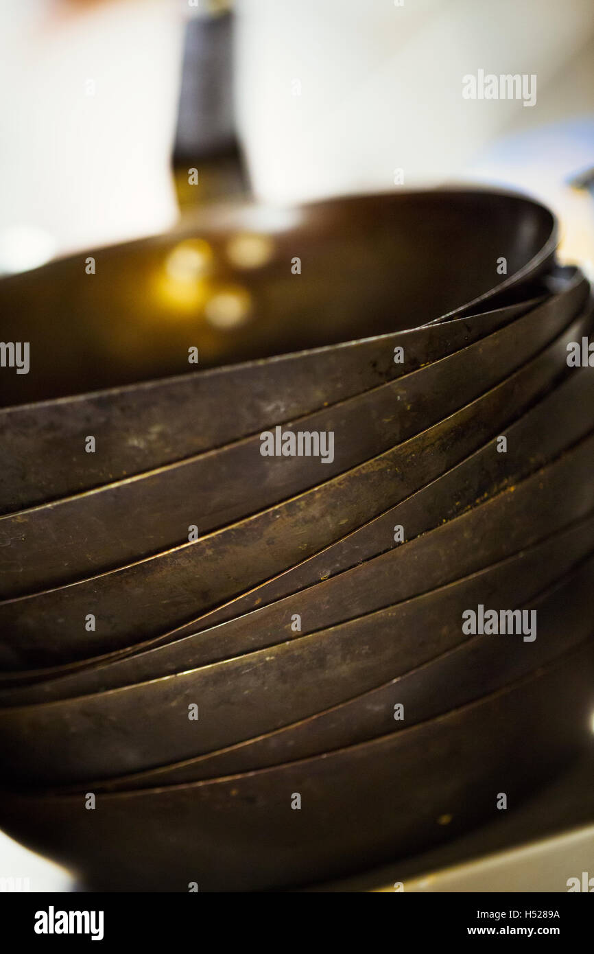 Close up of a stack of frying pans in a restaurant kitchen. Stock Photo