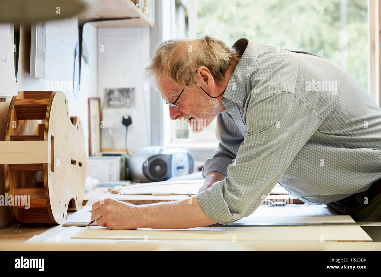 A violin maker at his drawing board drawing out the plans and outline for a new instrument. Stock Photo