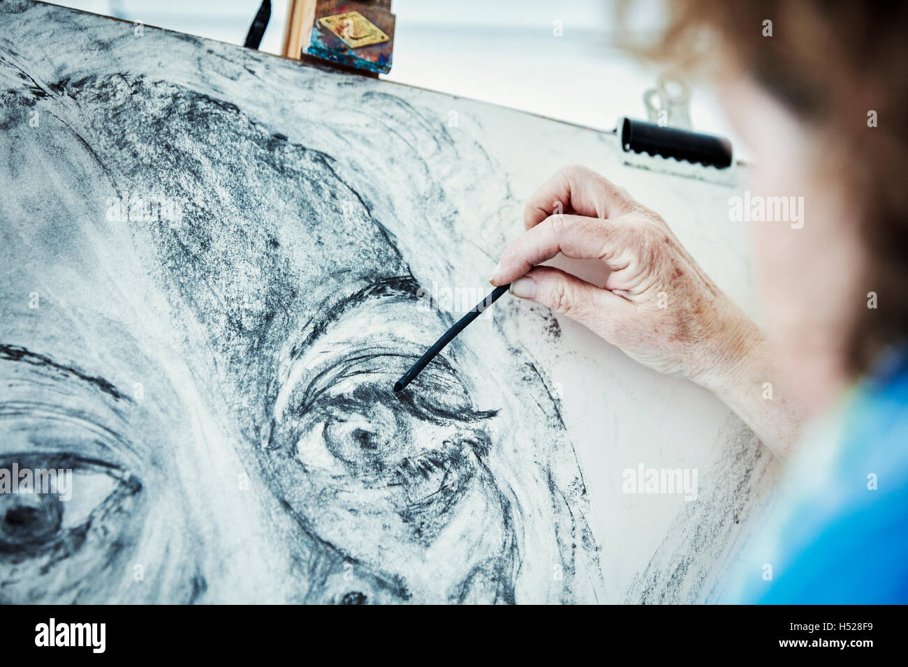 An artist working at her easel, drawing with charcoal on paper Stock Photo