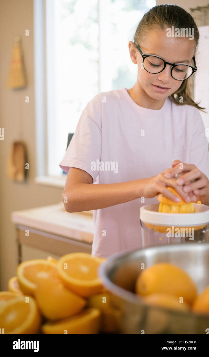 Family preparing breakfast in a kitchen, girl squeezing oranges. Stock Photo