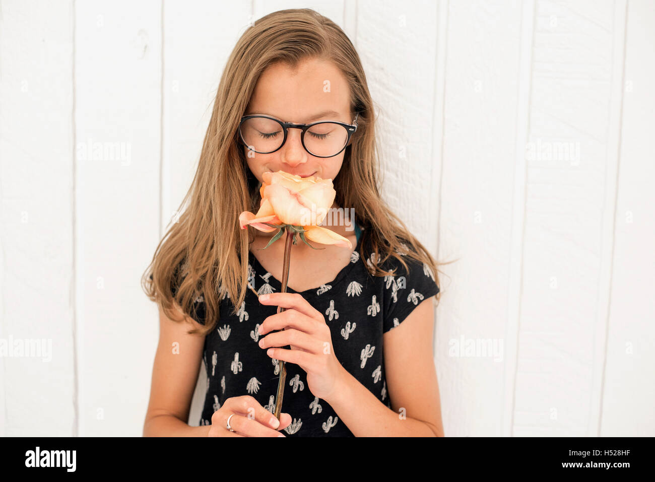 Girl with spectacles smelling a rose. Stock Photo