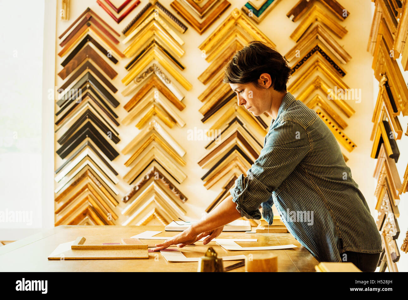 Woman working at a picture framers, a large selection of frames on the walls Stock Photo Alamy