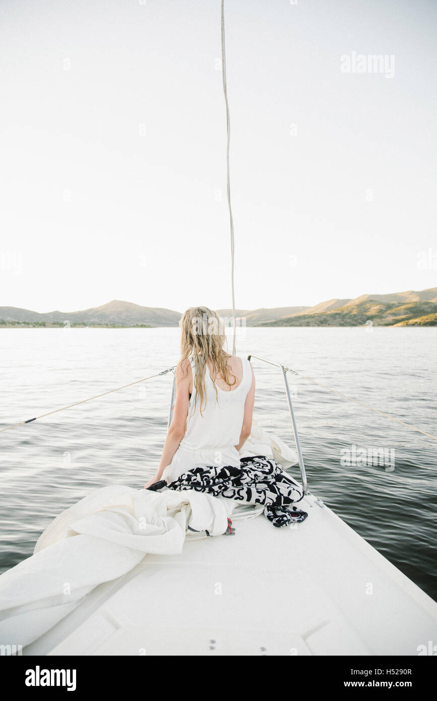 Blond teenage girl sitting on sail boat. Stock Photo