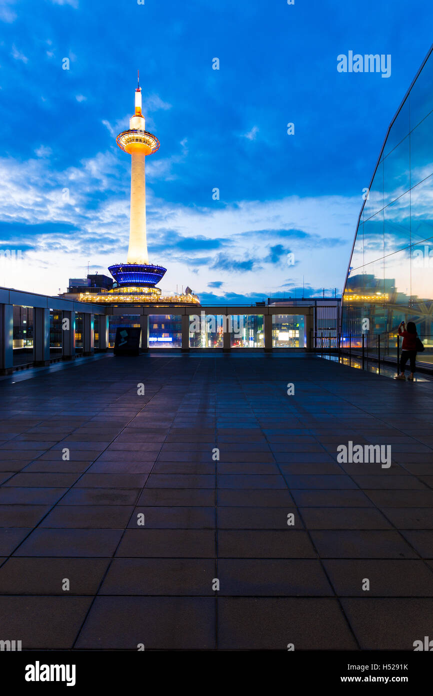 Lovely blue hour sky behind colorful, lighted Kyoto Tower seen from wide balcony in Kyoto, Japan. Vertical copy space Stock Photo