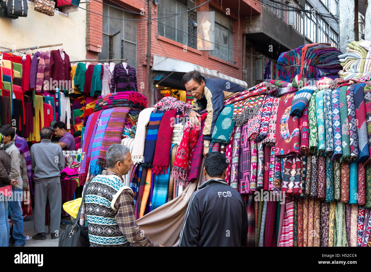 Kathmandu, Nepal - October 19, 2014: A seller showing scarfs to customers on the market in Thamel district Stock Photo