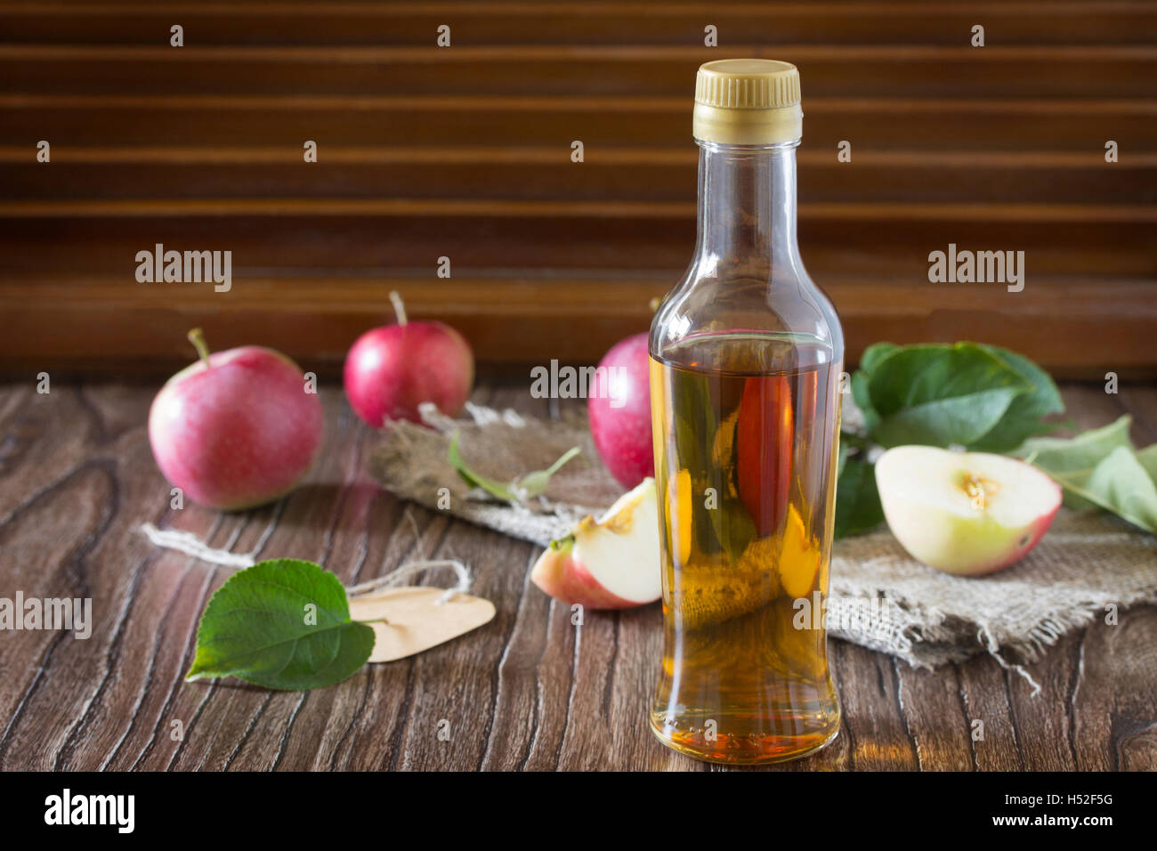 Apple cider vinegar in a glass bottle with fresh apples on a table in a ...