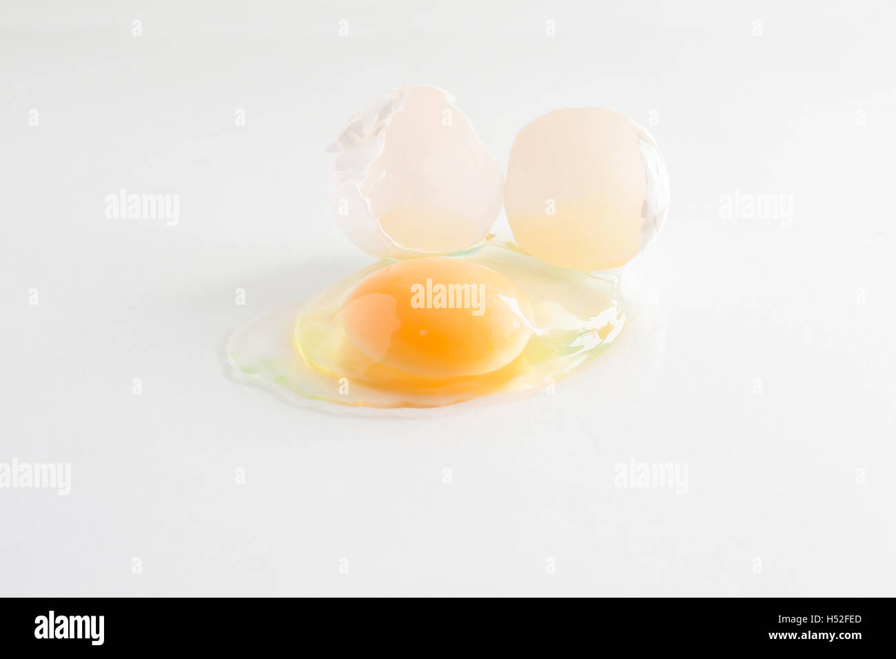 white egg is broken and leaked on a white background Stock Photo - Alamy