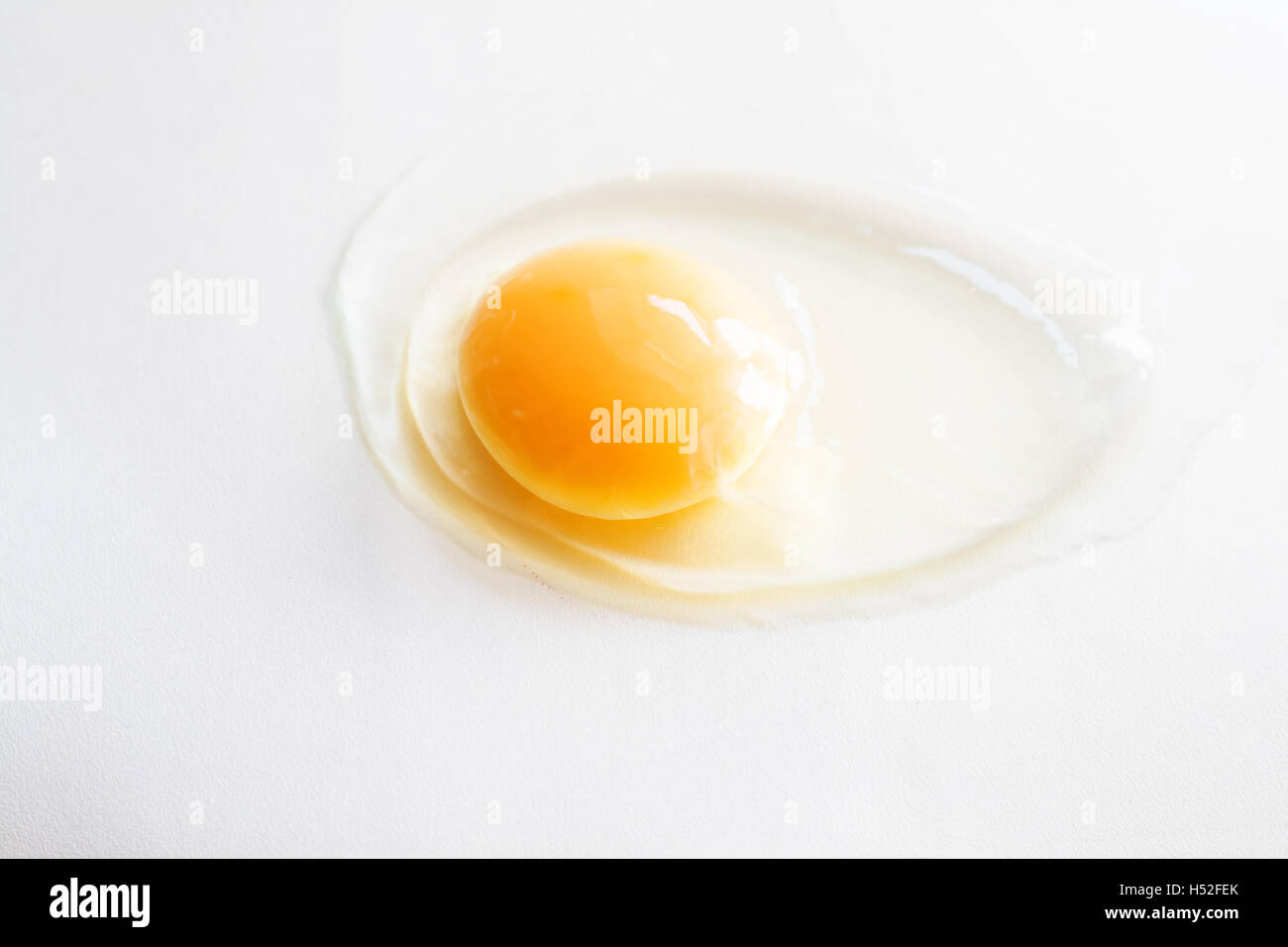 white egg is broken and leaked on a white background Stock Photo - Alamy