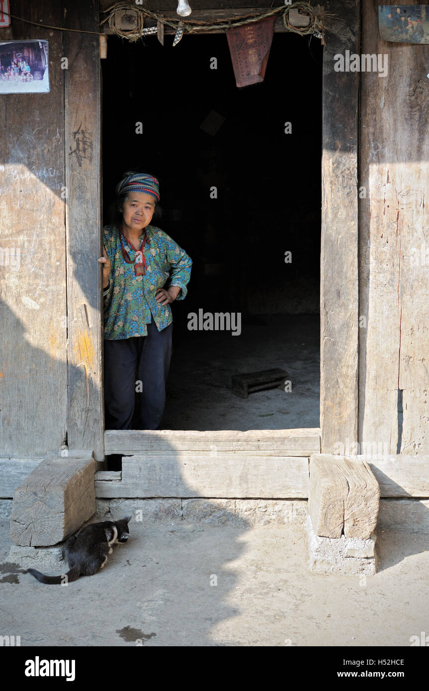 Hmong woman and cat at the door of a traditional house in Ha Giang province, North Vietnam Stock Photo