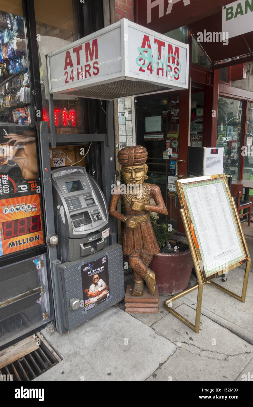 ATM machine and statue in front of an Indian restaurant in the East Village along 2nd Ave. in NY City. Stock Photo