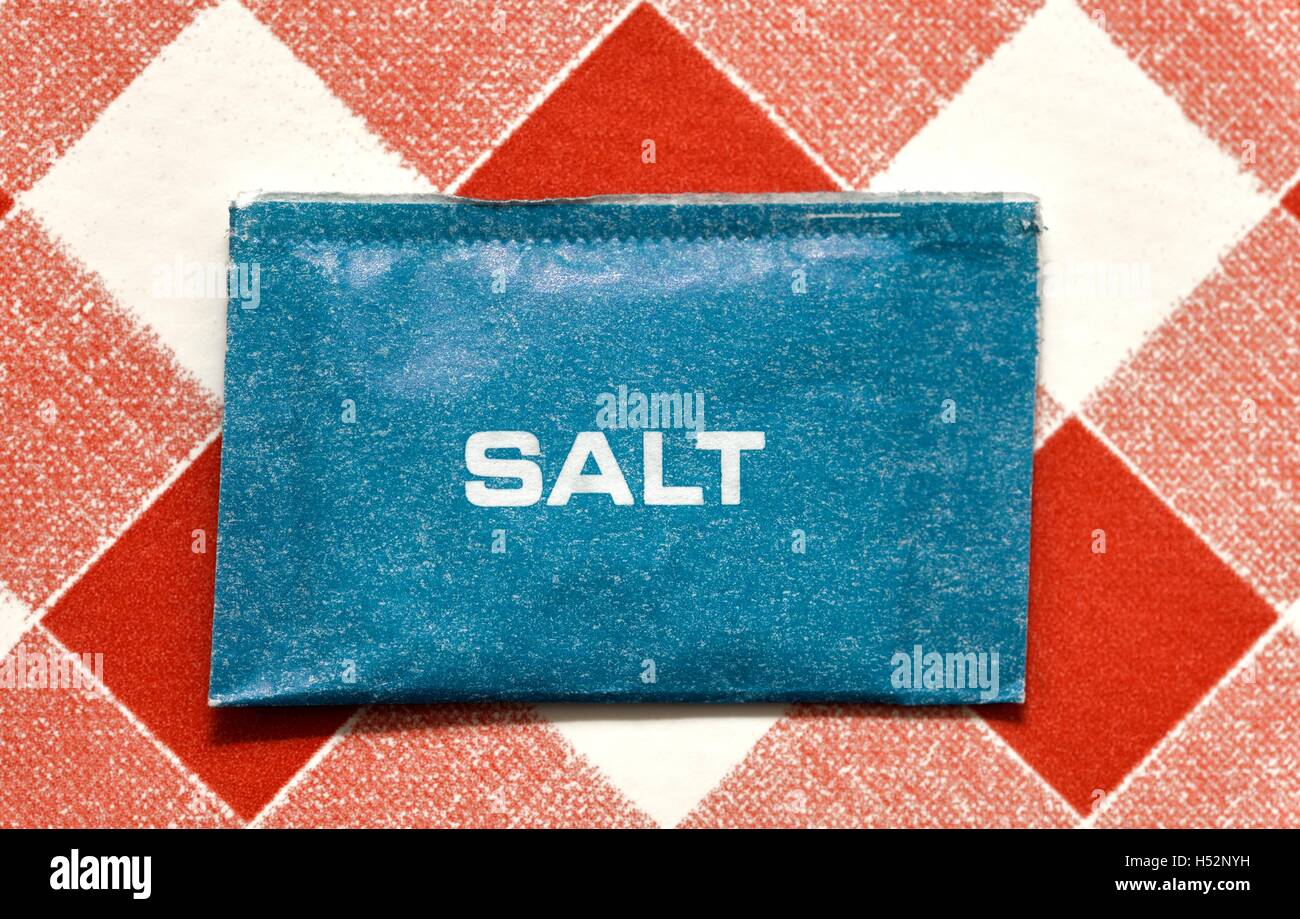 A Sachet of catering salt on a red gingham background. Stock Photo