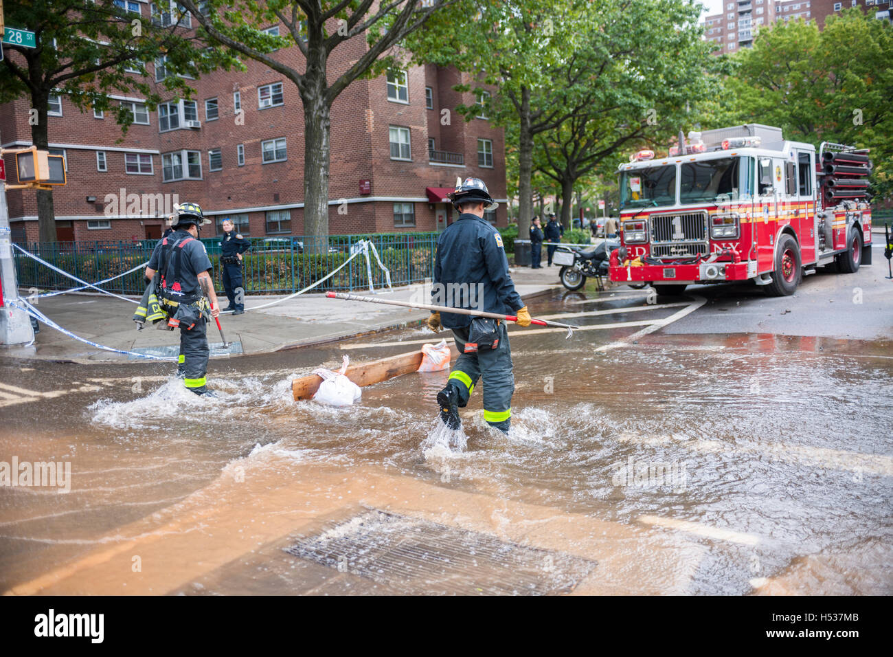 FDNY firefighters respond to a watermain break  in the Chelsea neighborhood of New York on Wednesday, October 12, 2016. The watermain break caused water to gush but it was mostly contained to the street safely running into storm drains. (© Richard B. Levine) Stock Photo