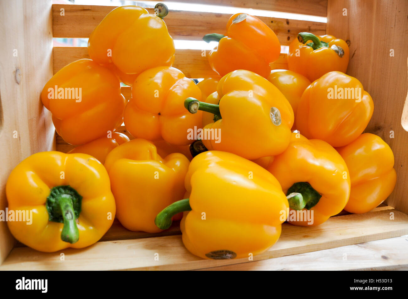 Closeup of wood crate with yellow bell peppers at farmers market Stock Photo