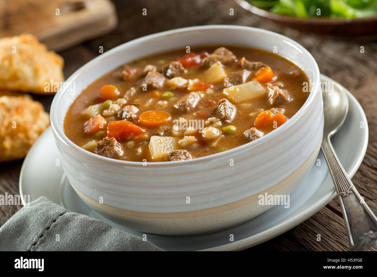 A bowl of delicious beef and barley soup with carrots, tomato, potato