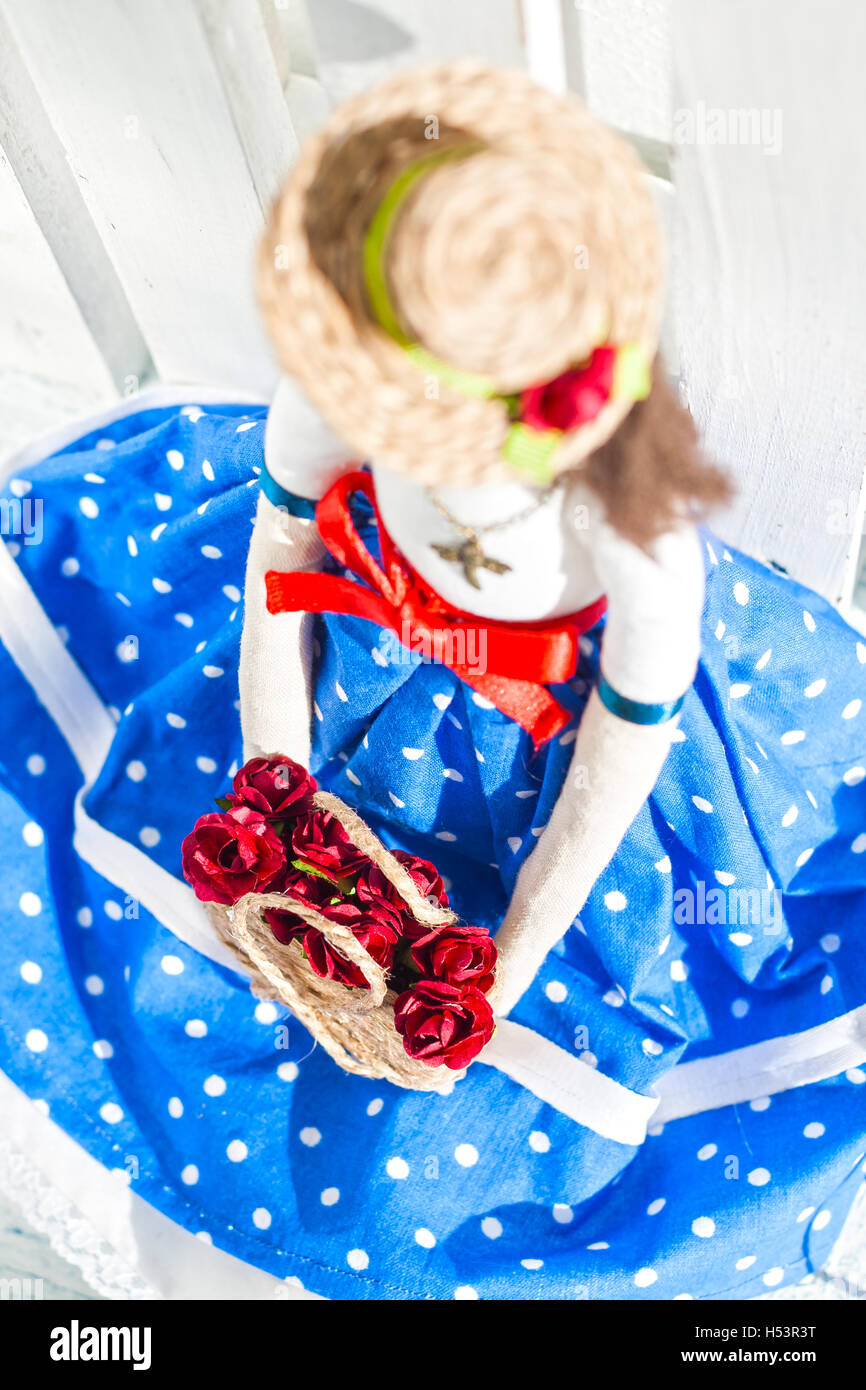 tilde doll in a blue skirt and a straw hat with a basket with flowers/ Stock Photo