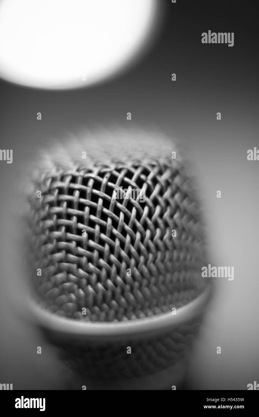 Modern black and white studio microphone head macro close up with out of focus light on the top in background Stock Photo