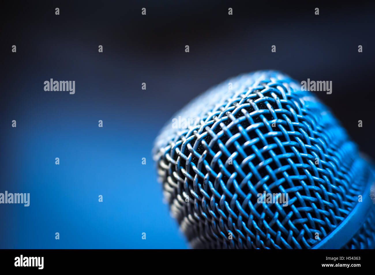 Modern black studio microphone head macro close up with out of focus cold blue background Stock Photo