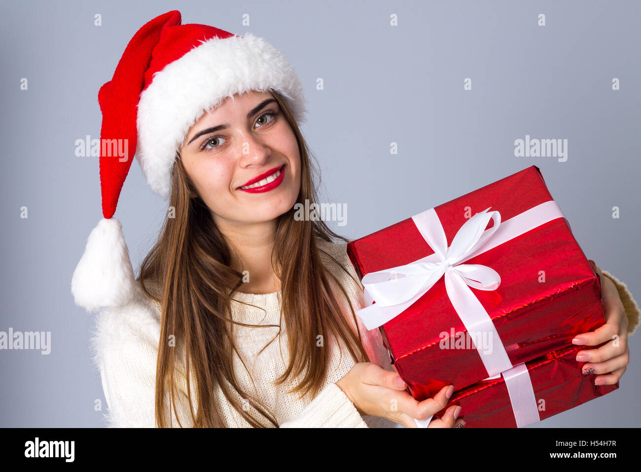 Woman in red christmas hat holding presents Stock Photo