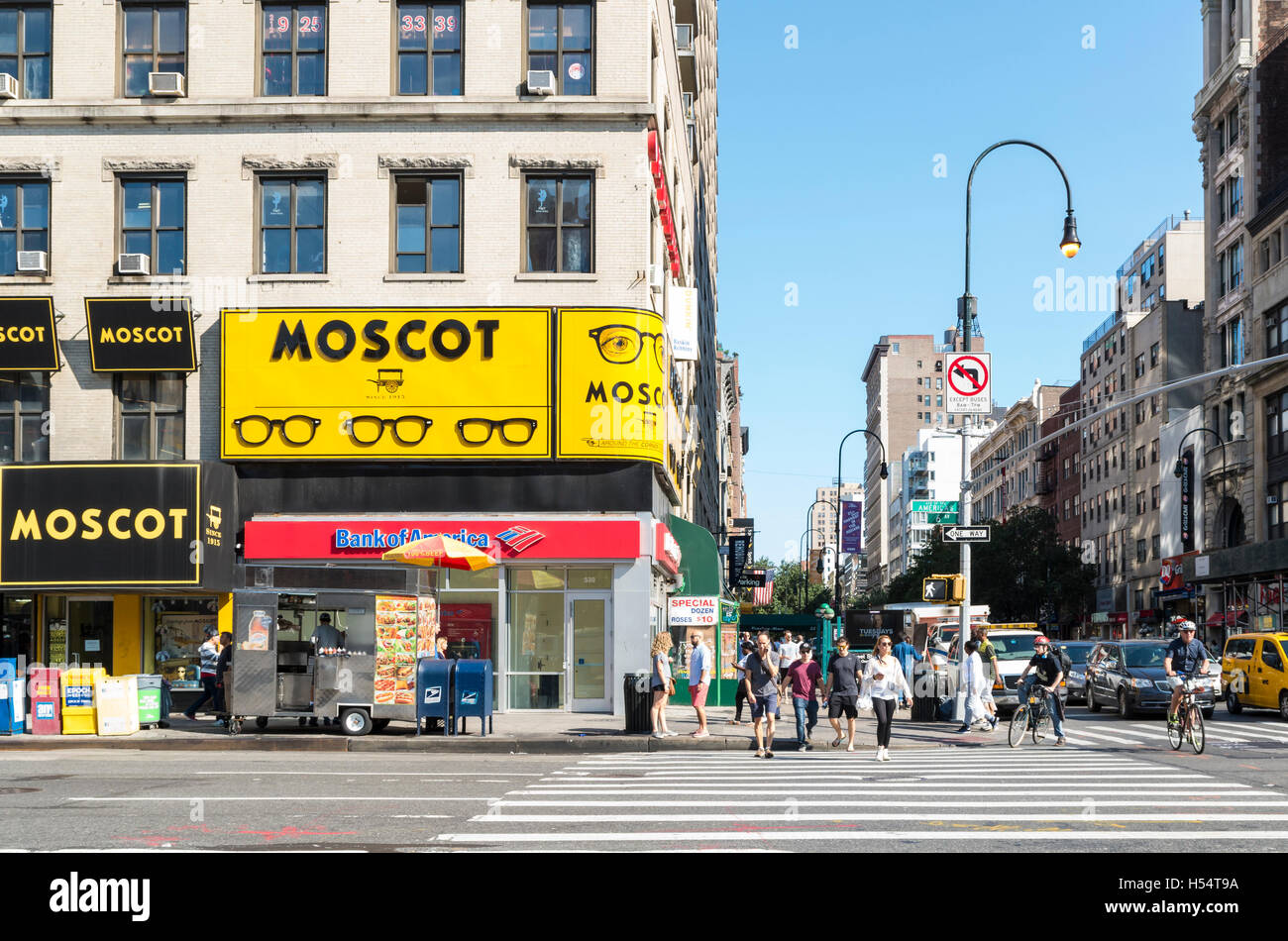 View of intersection of 14th Street with 6th Avenue, with Moscot eyeglasses store and people crossing the road Stock Photo