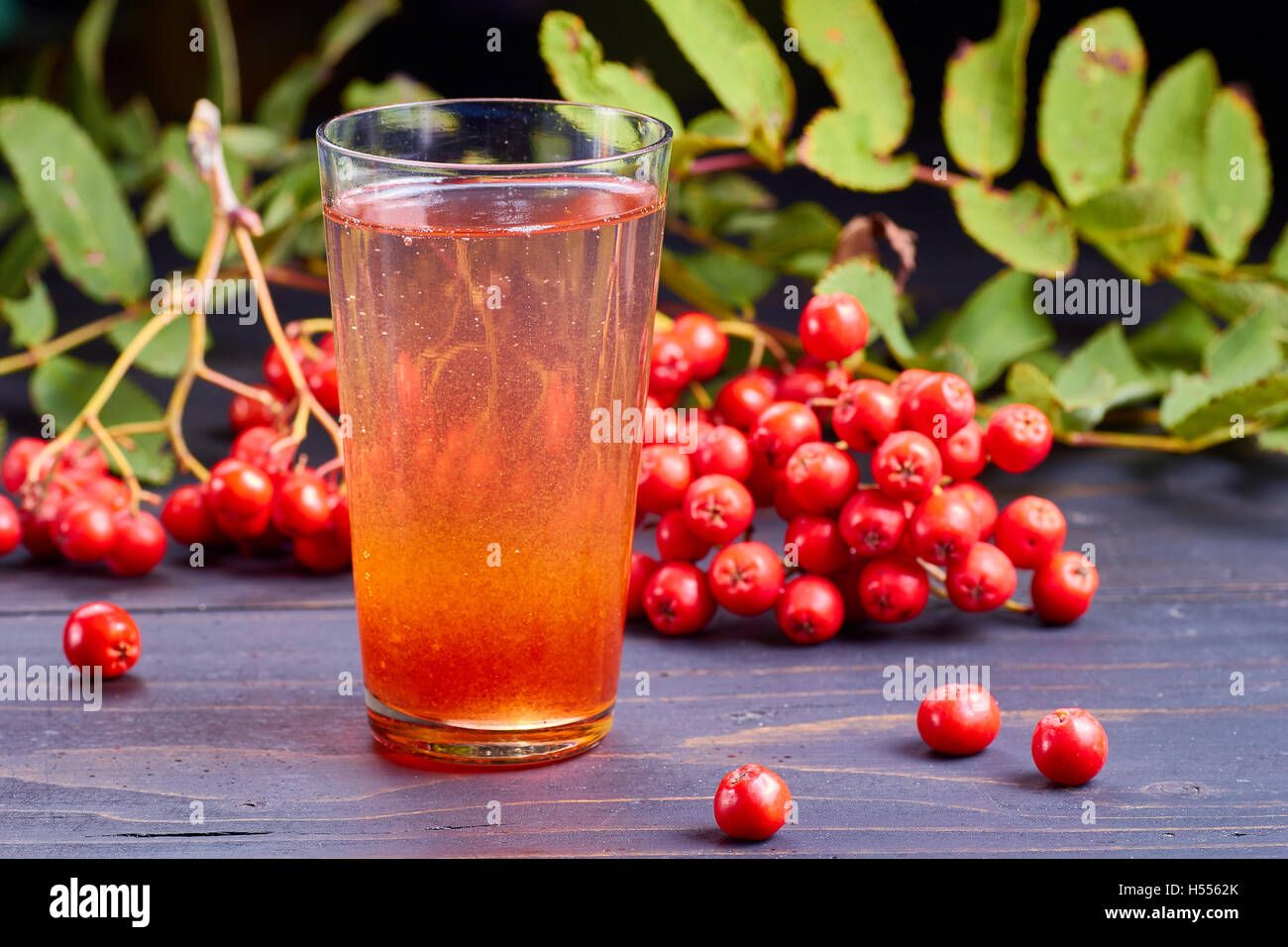 Glass of  drink with rowan syrup on dark wooden table Stock Photo