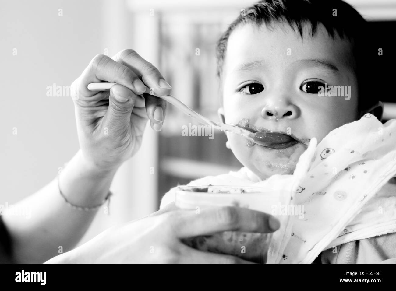baby looking while feeding Eating Healthy Porridge Food, soft black and white color low key style. Stock Photo