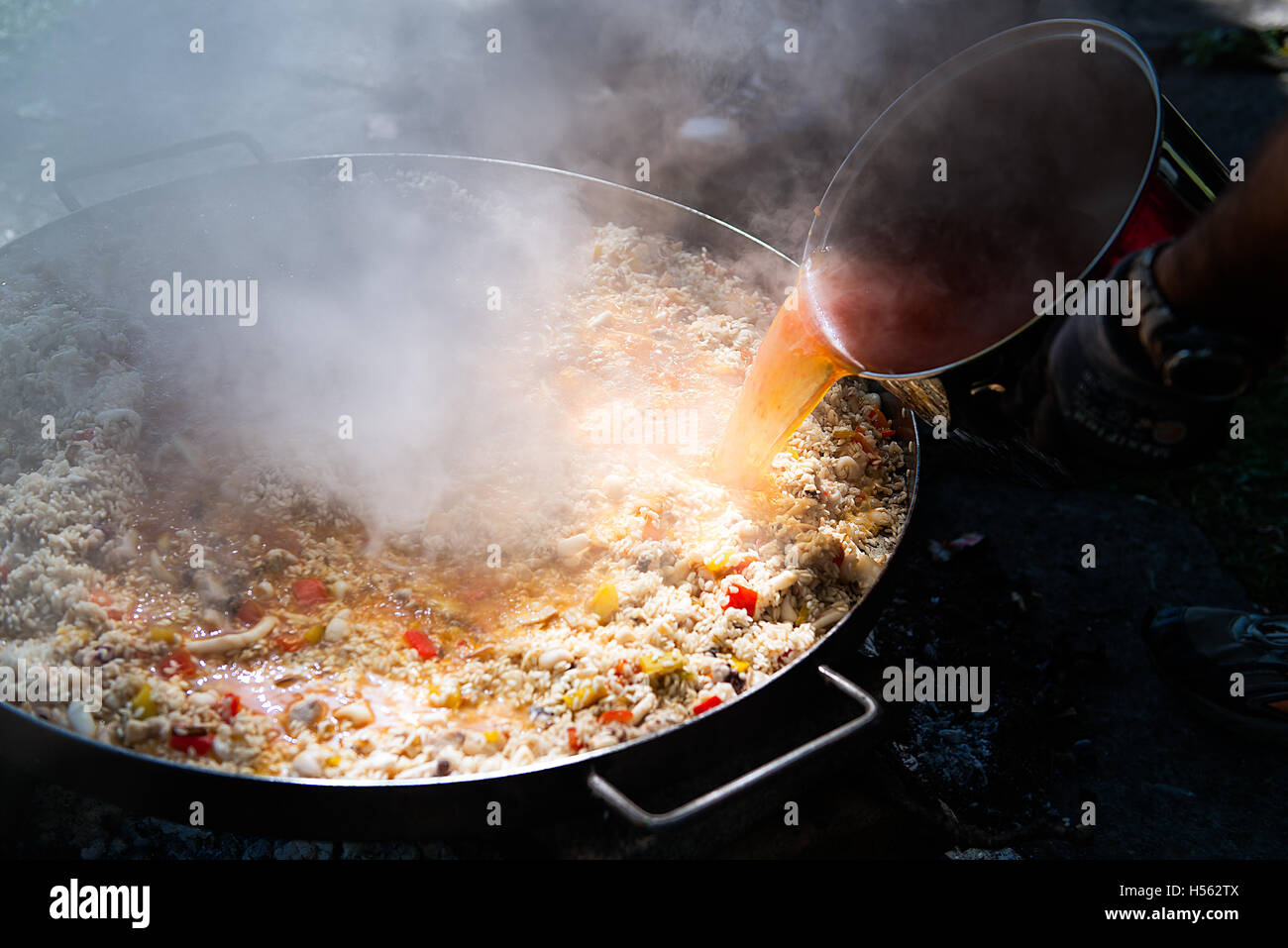 Preparing paella pouring the hot broth Stock Photo Alamy