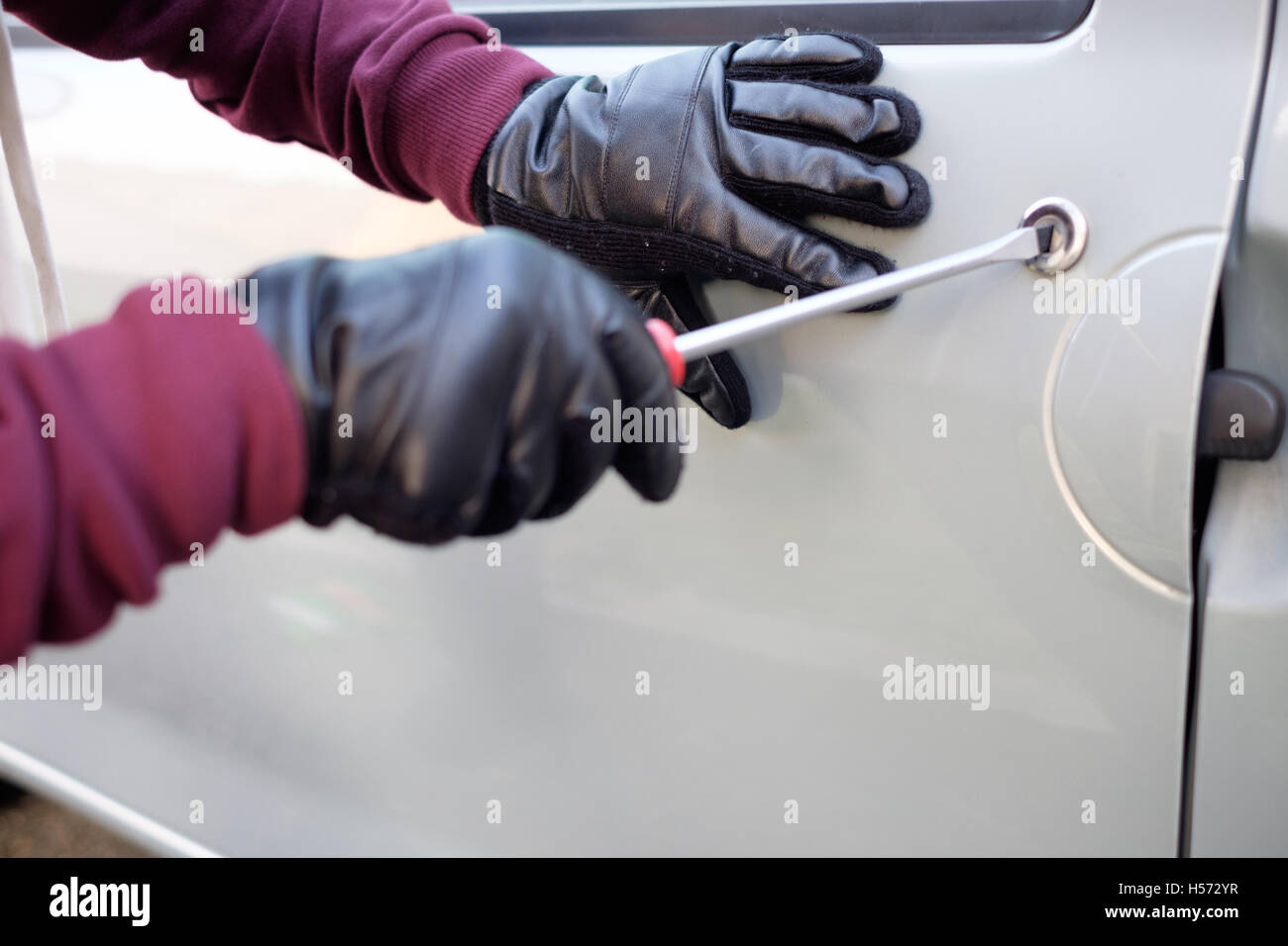 Hands of a thief trying to open a car door lock Stock Photo