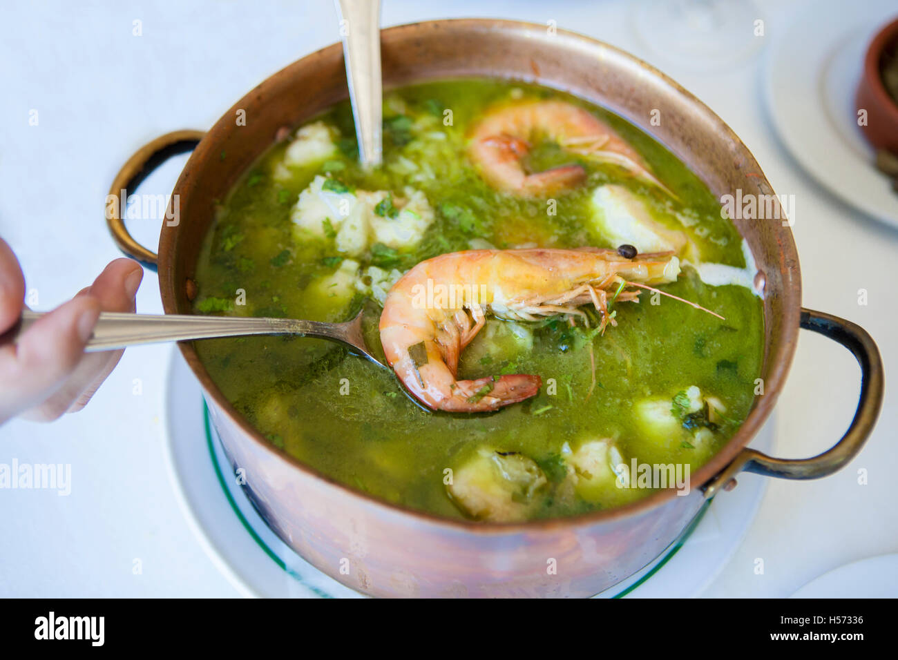 Arroz de Tamboril or soupy seafood rice, portuguese recipe. Hand holding the spoon with a prawn Stock Photo