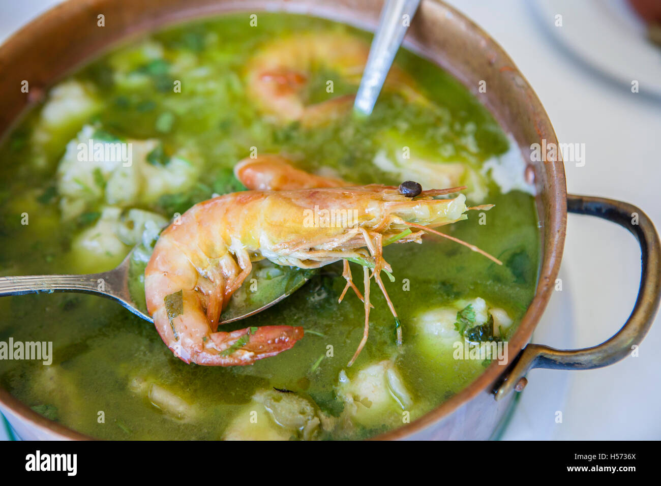 Arroz de Tamboril or soupy seafood rice, portuguese recipe. Spoon holding a prawn Stock Photo