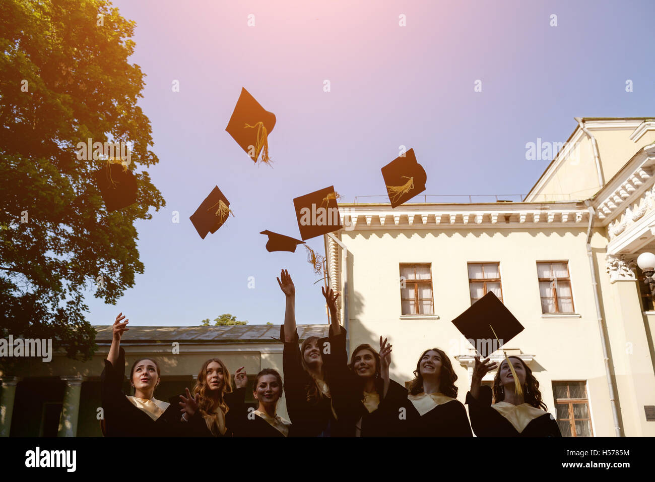 group of happy graduates throwing graduation hats in the air ...