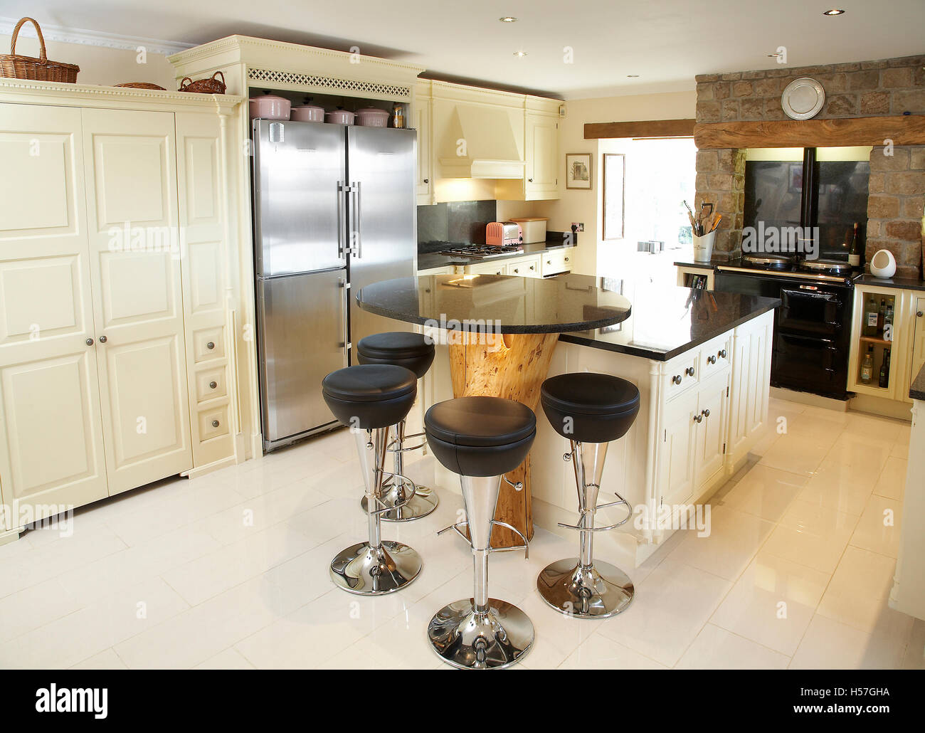 A bespoke country kitchen in a house in the UK using the trunk of a tree as a breakfast island. Stock Photo