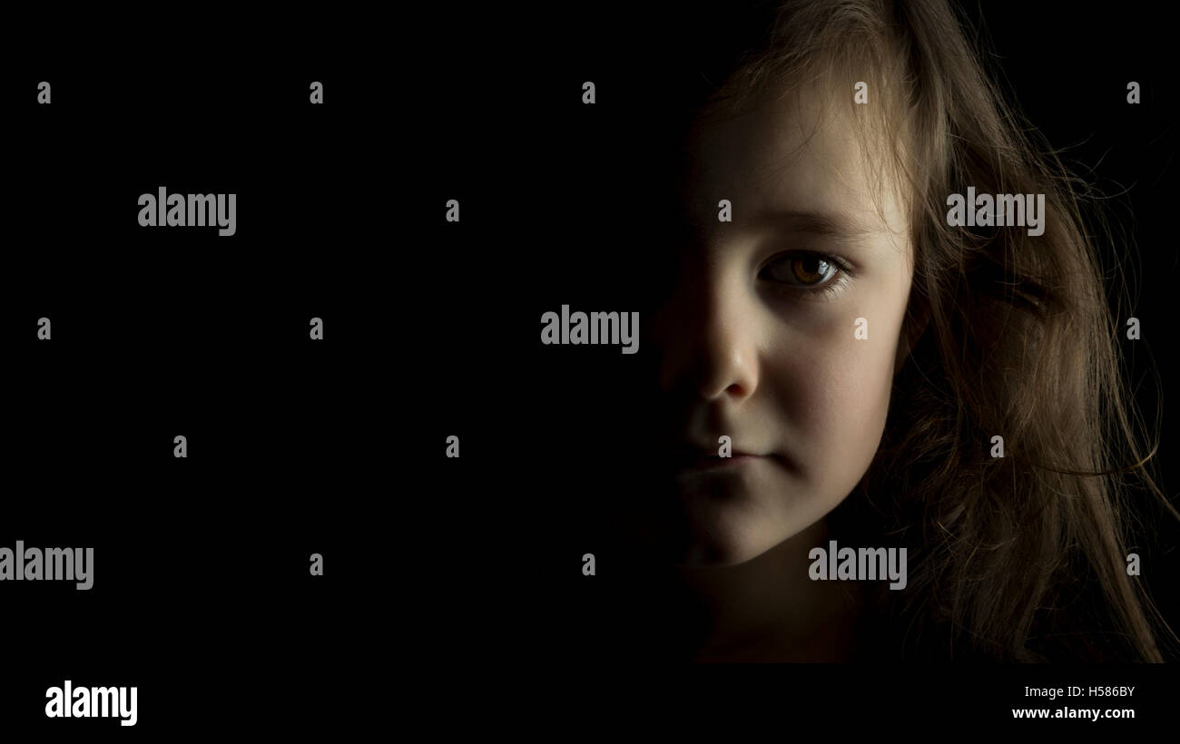 Portrait of young girl in studio on black background with copy space ...