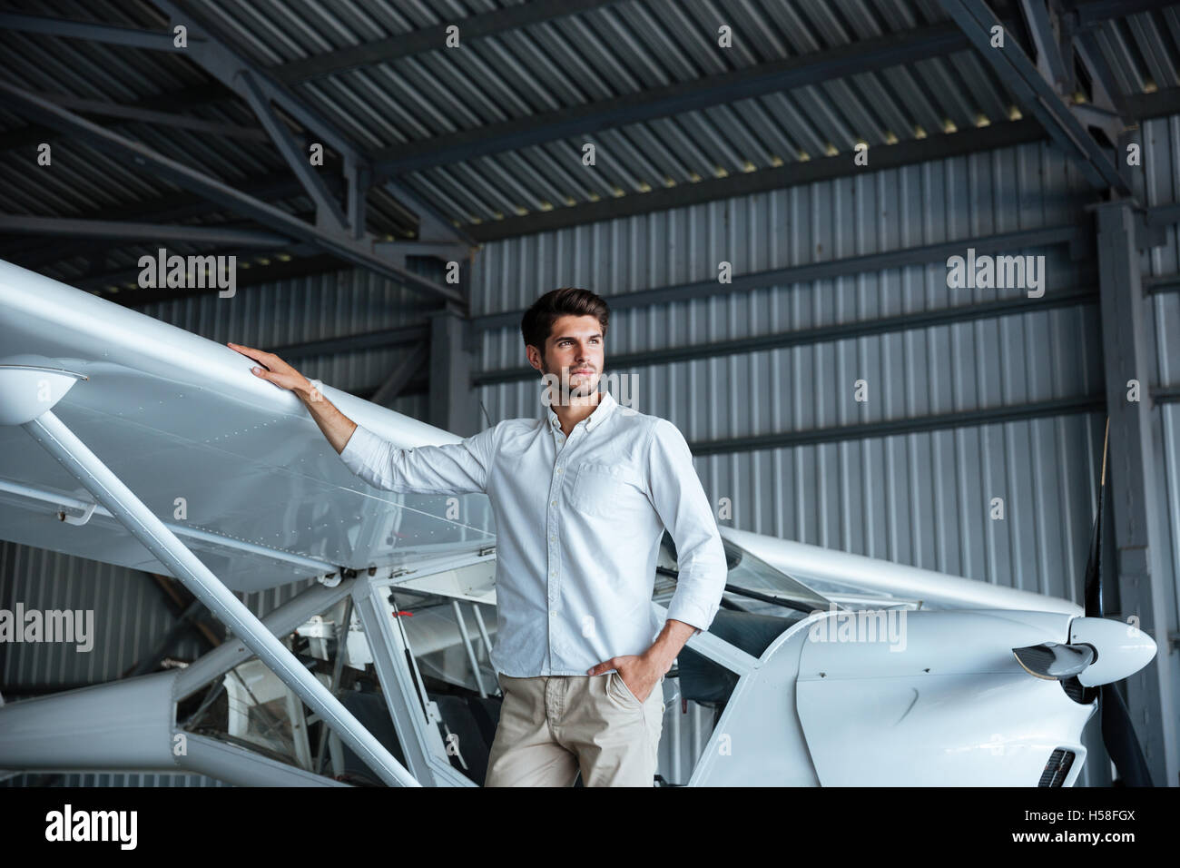 Portrait of handsome young man standing near smal airplane Stock Photo