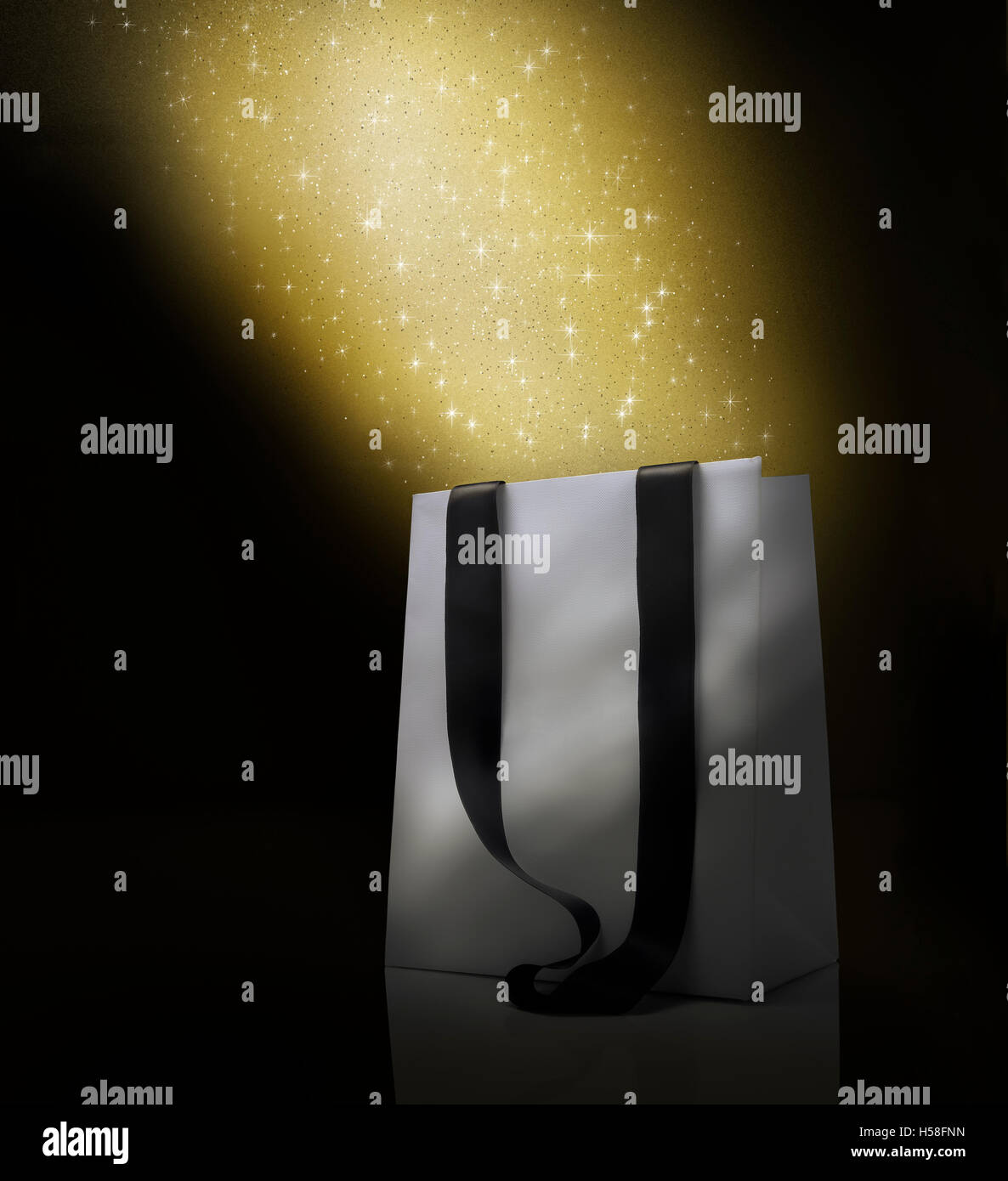 Fantasy Christmas shopping bag . Stardust's effect over white bag. Black background and copy space Stock Photo