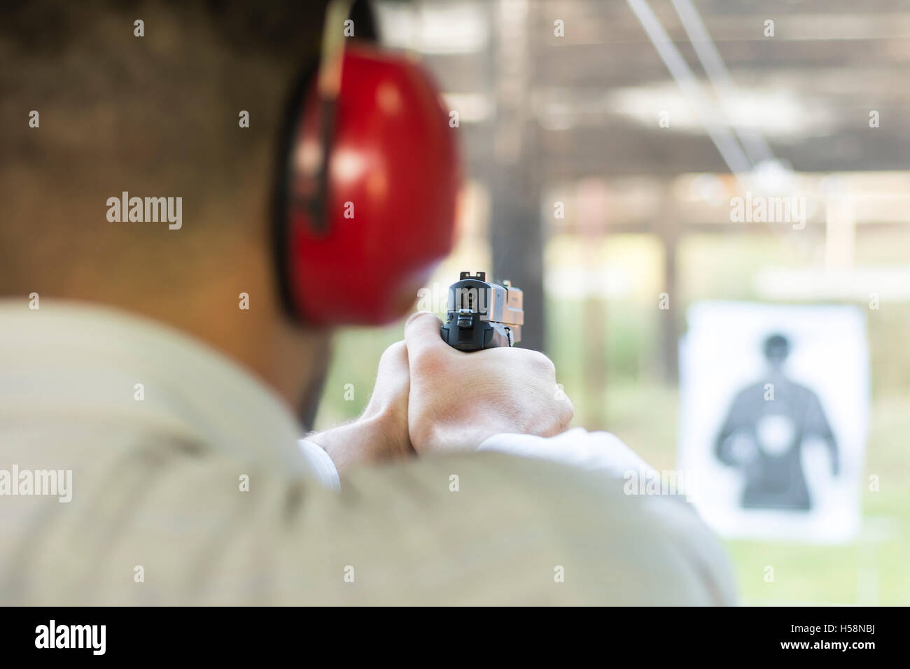 Shooting with Gun at Target in Shooting Range. Man Practicing Fire Pistol Shooting. Stock Photo