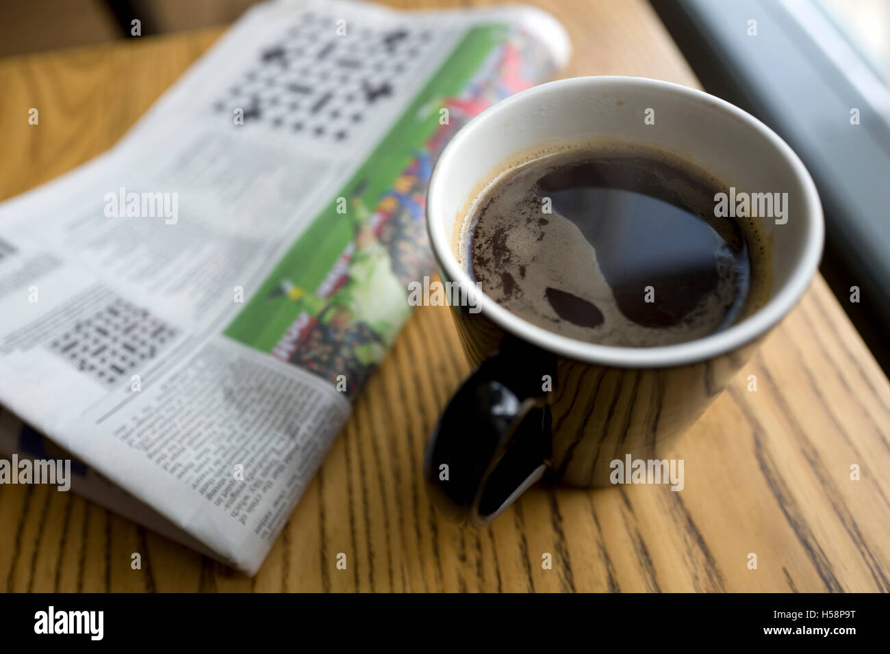 Black coffee and newspaper in cafe, UK Stock Photo