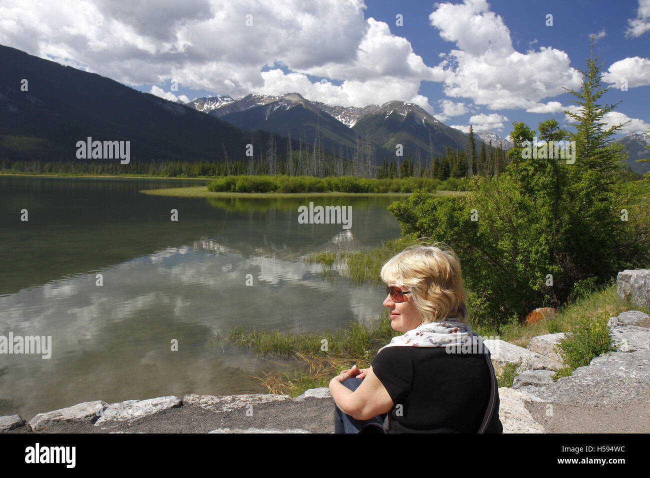 Mature woman sitting by the edge of Vermillion Lakes, Banff, Canada Stock Photo