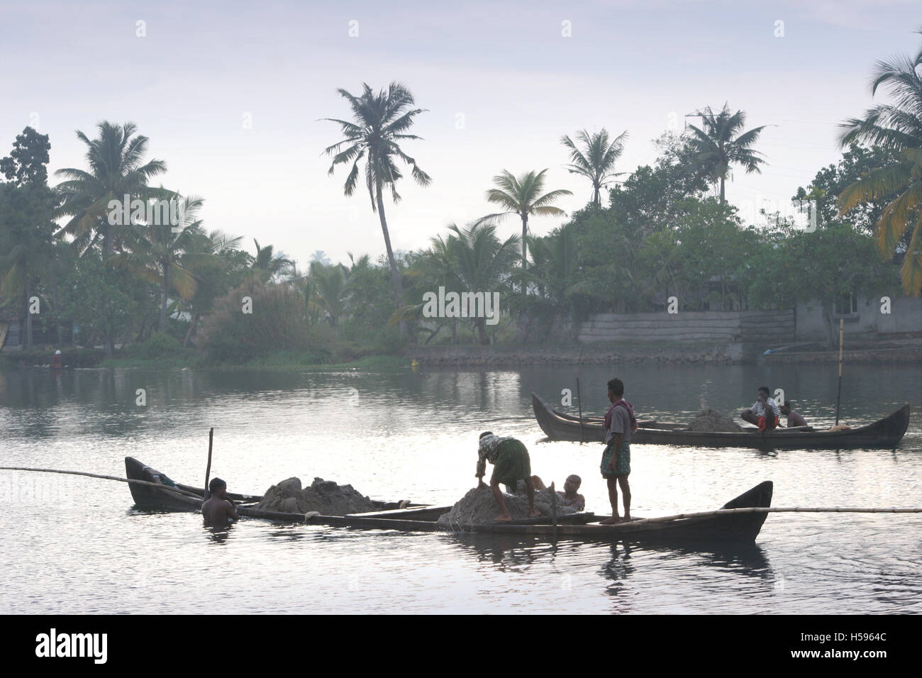 Local workmen hand-dig for sand at dawn in the Kerela Backwaters near Kochi, southern India Stock Photo