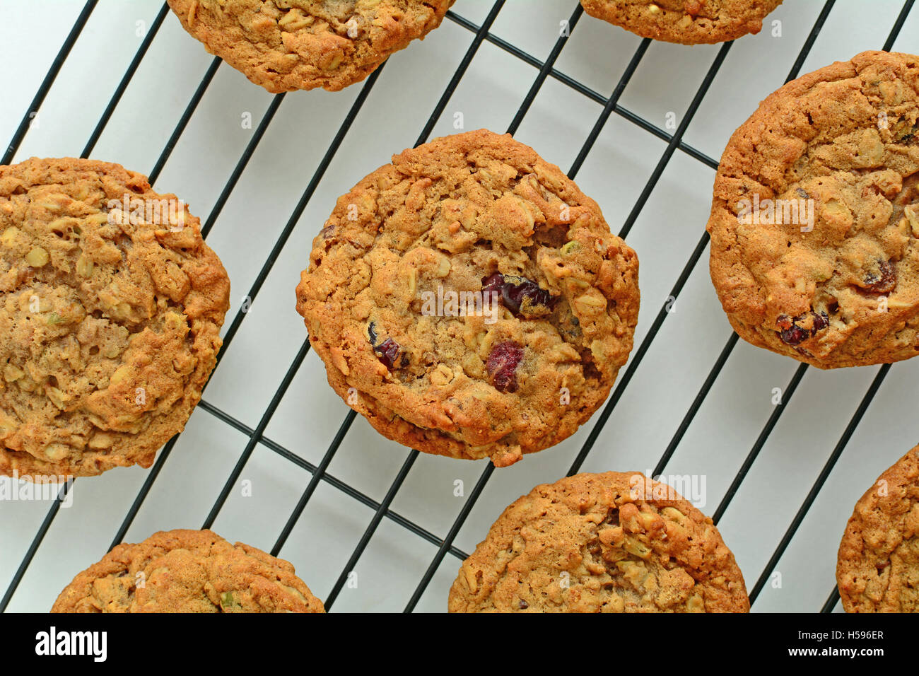 Fresh baked oatmeal raisin walnut cookies on black cooling rack shot from overhead in horizontal format Stock Photo