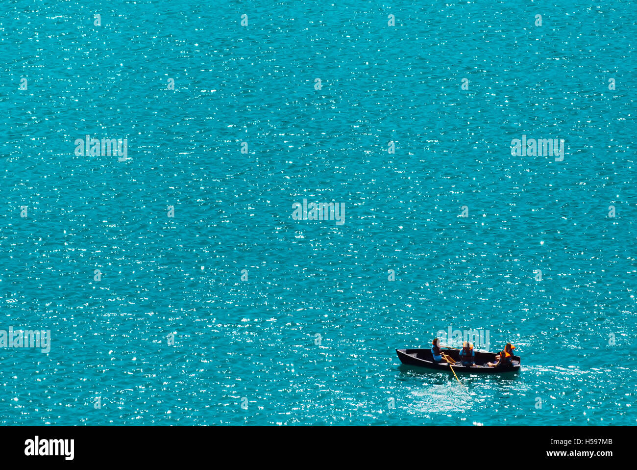 Unrecognizable people rowing in boat on lake, vast water surface as copy space Stock Photo