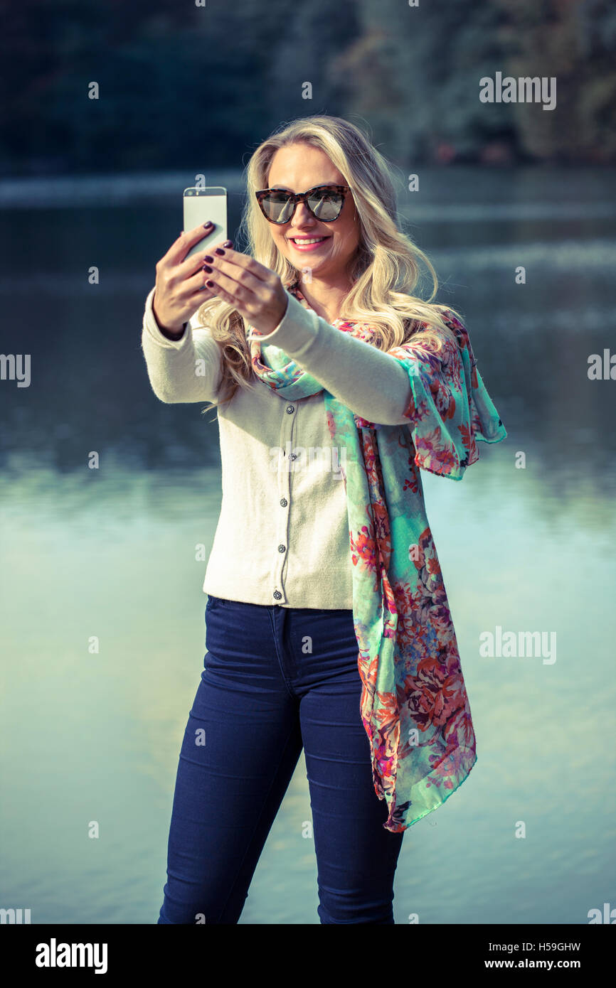 Beautiful young blonde making selfie in the park Stock Photo