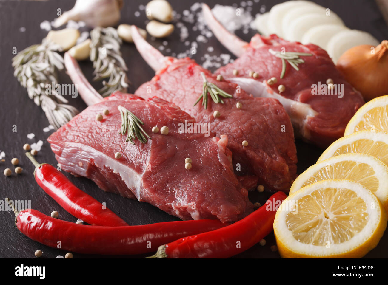 Raw beef steak with spices on a black stone table closeup. horizontal Stock Photo