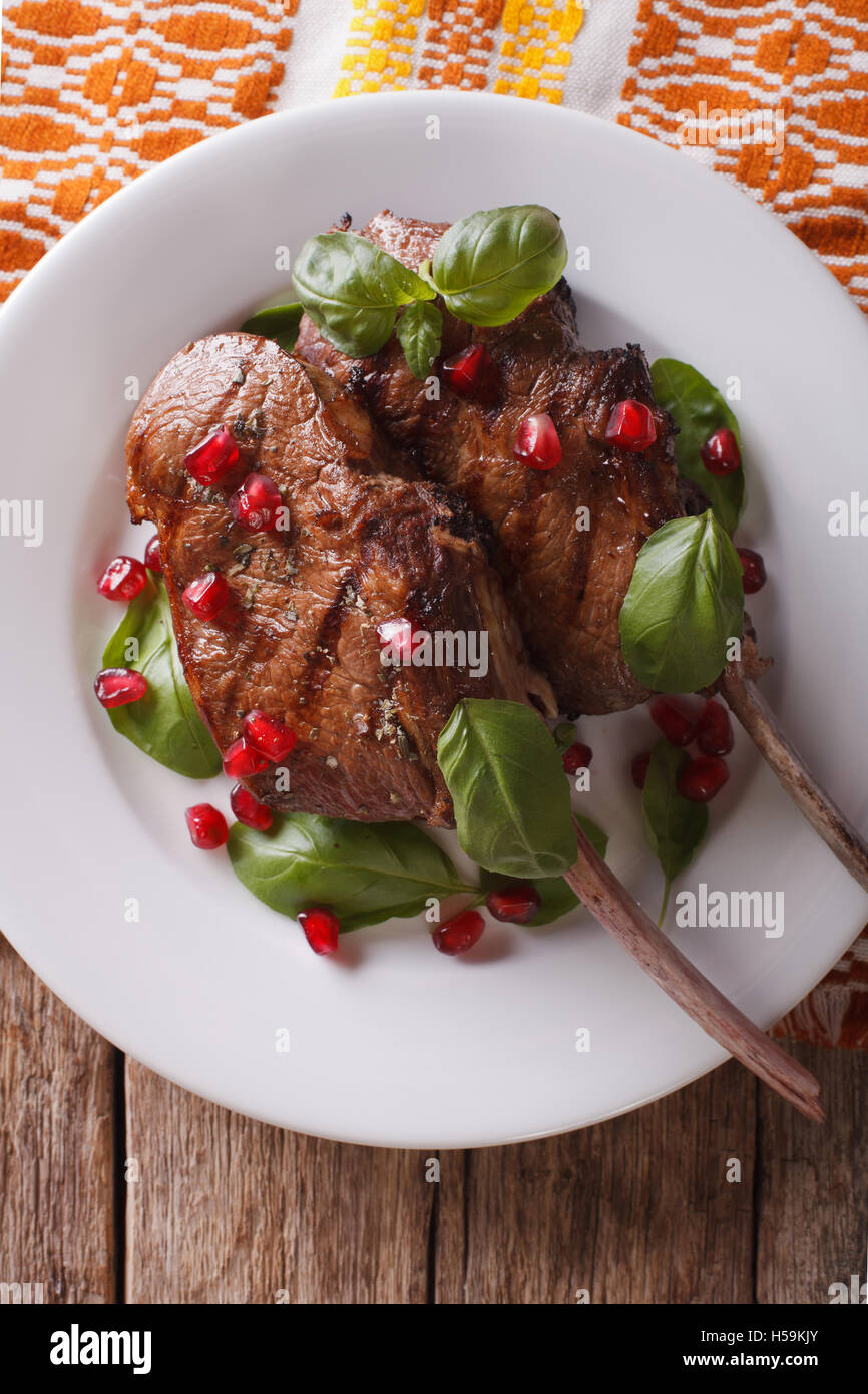 Grilled beef steak with pomegranate closeup on a plate on the table. vertical top view Stock Photo