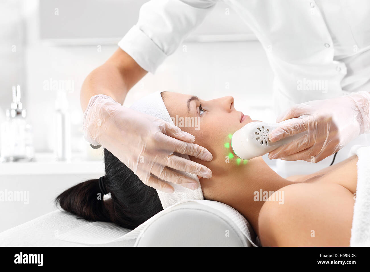 Ultrasonic massager Light skin treatment, the woman in the beauty salon Stock Photo